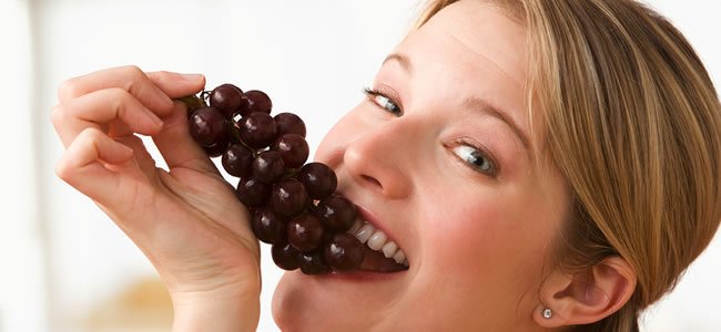 Mulher comendo uvas.